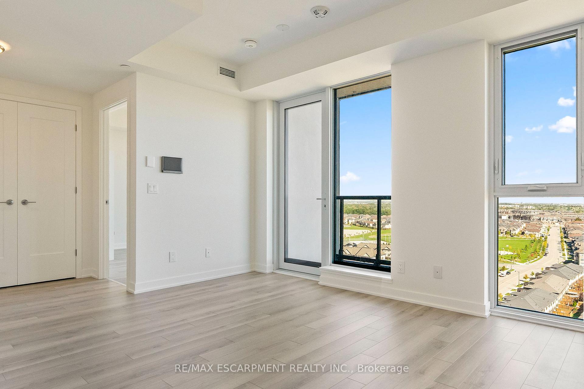 Unfurnished condo room with pale flooring, large windows, and a balcony overlooking the neighborhood.