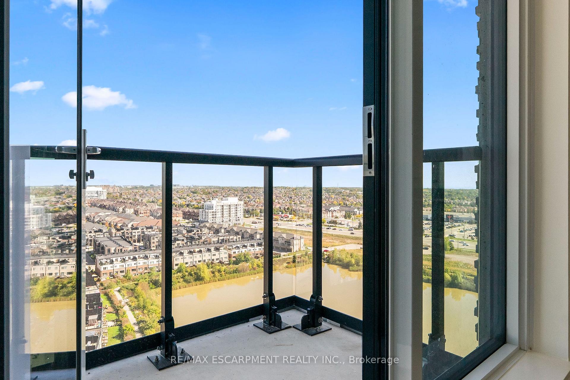 High-rise condo balcony overlooking Oakville buildings and a winding body of water.