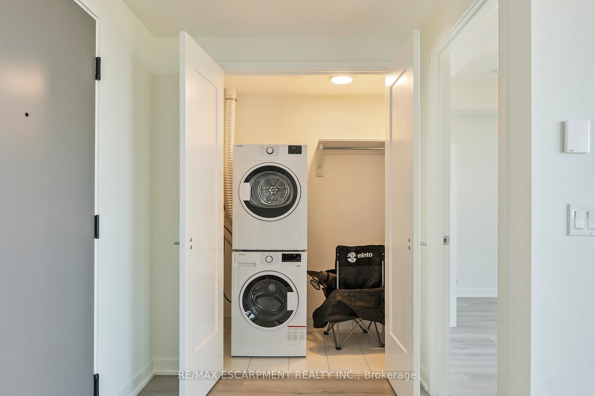 Laundry closet with stacked washer and dryer, hanging rod, and black folding chair.