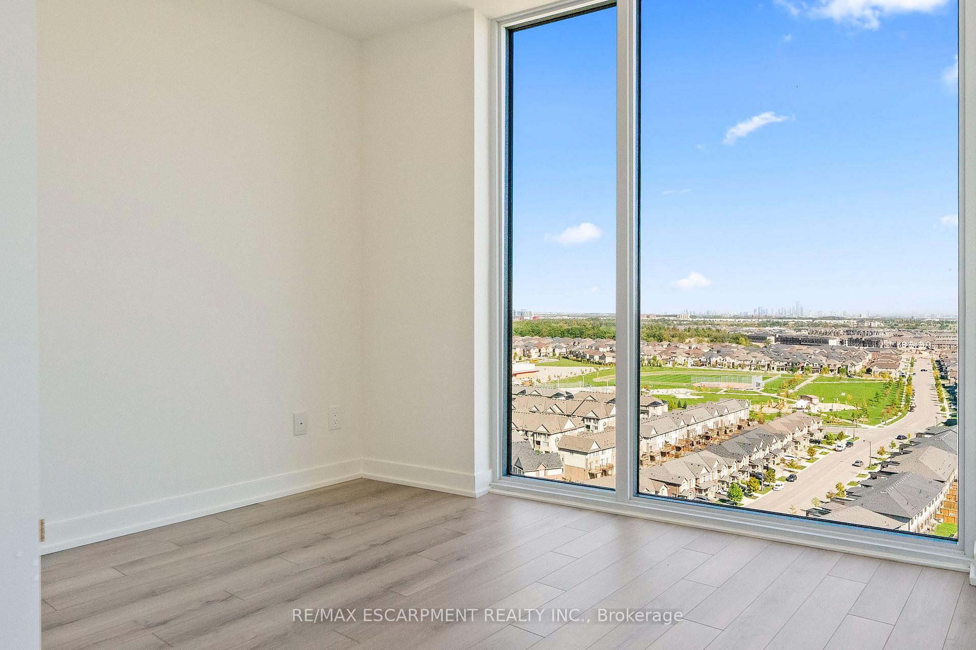 Unfurnished room with floor-to-ceiling windows overlooking suburban homes and green space.