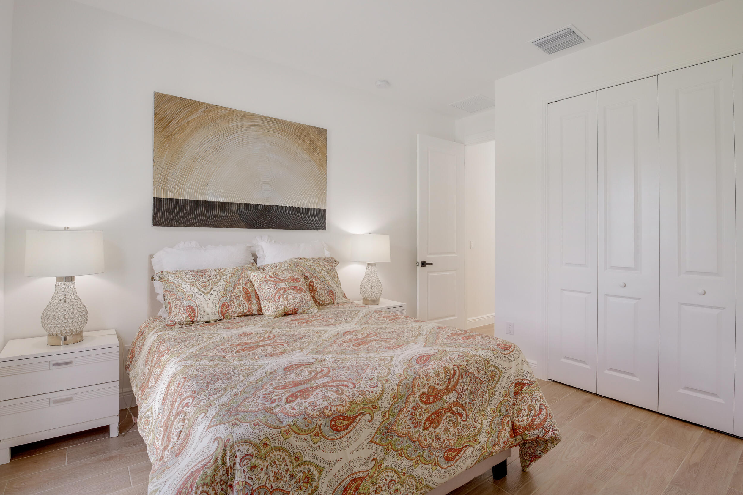 Bedroom with paisley bedding, matching bedside lamps, and white closet doors.