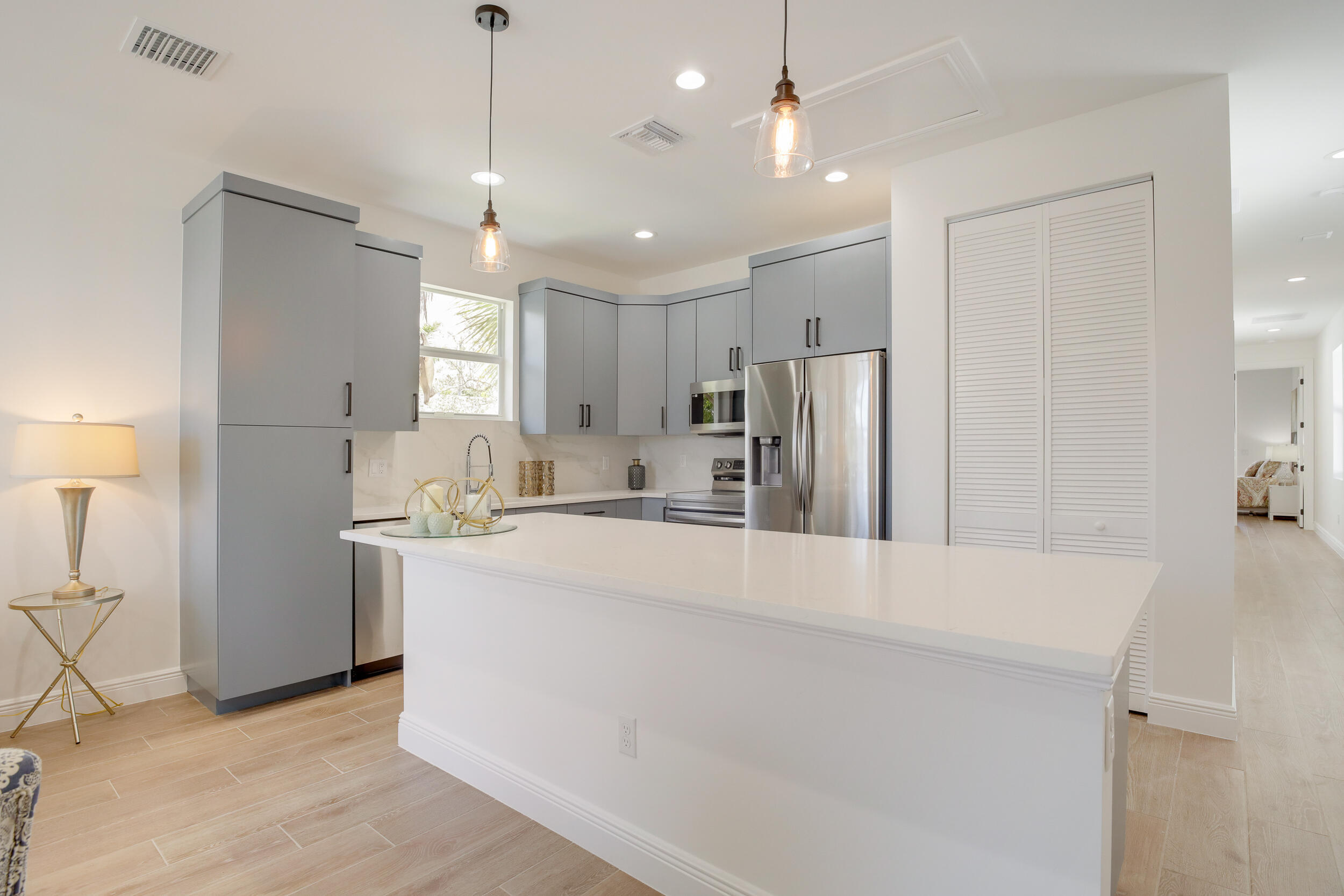Modern kitchen with gray cabinets, stainless steel appliances, and a large white island.