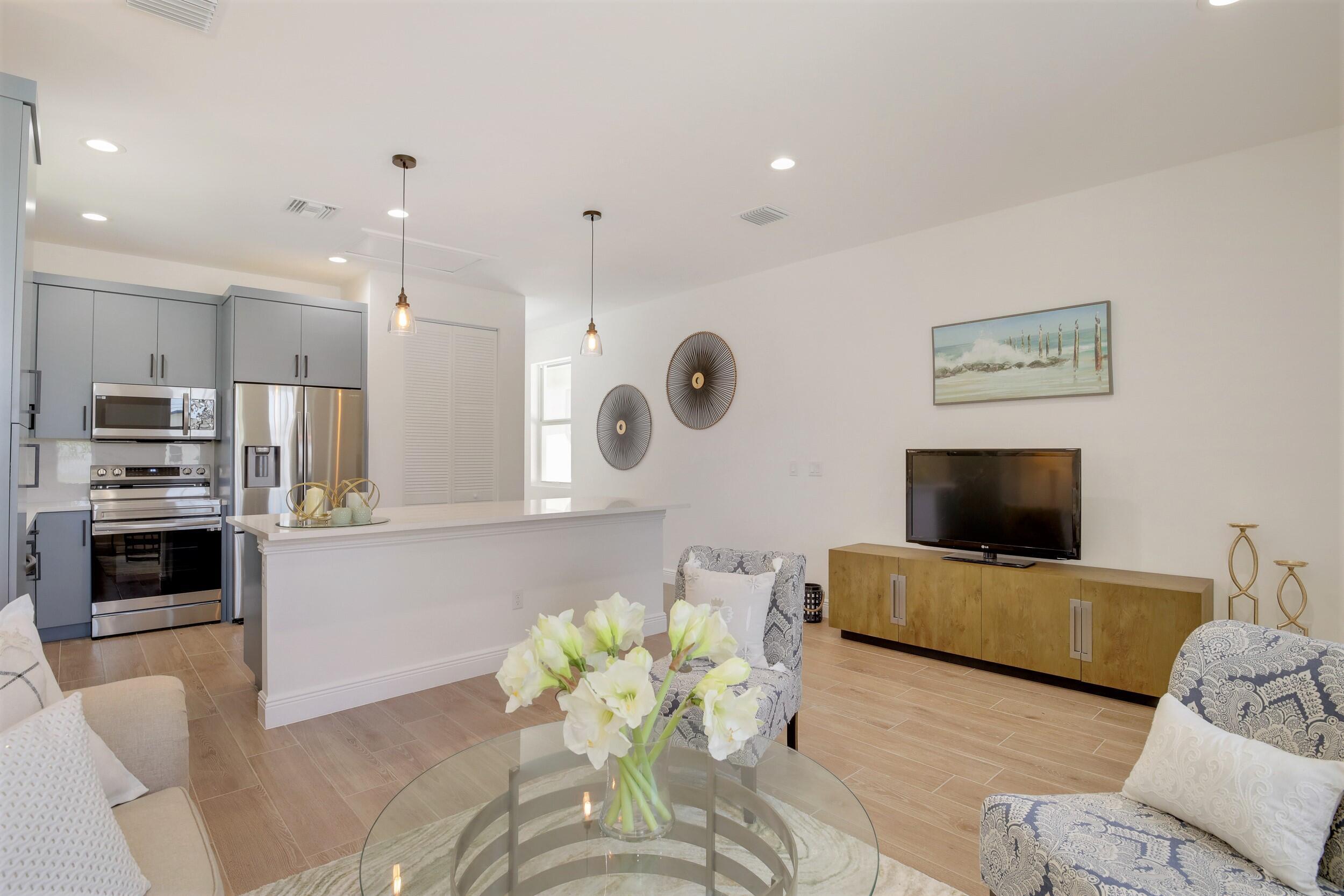 Open-plan kitchen and living room with gray cabinetry, stainless appliances, and a white island.