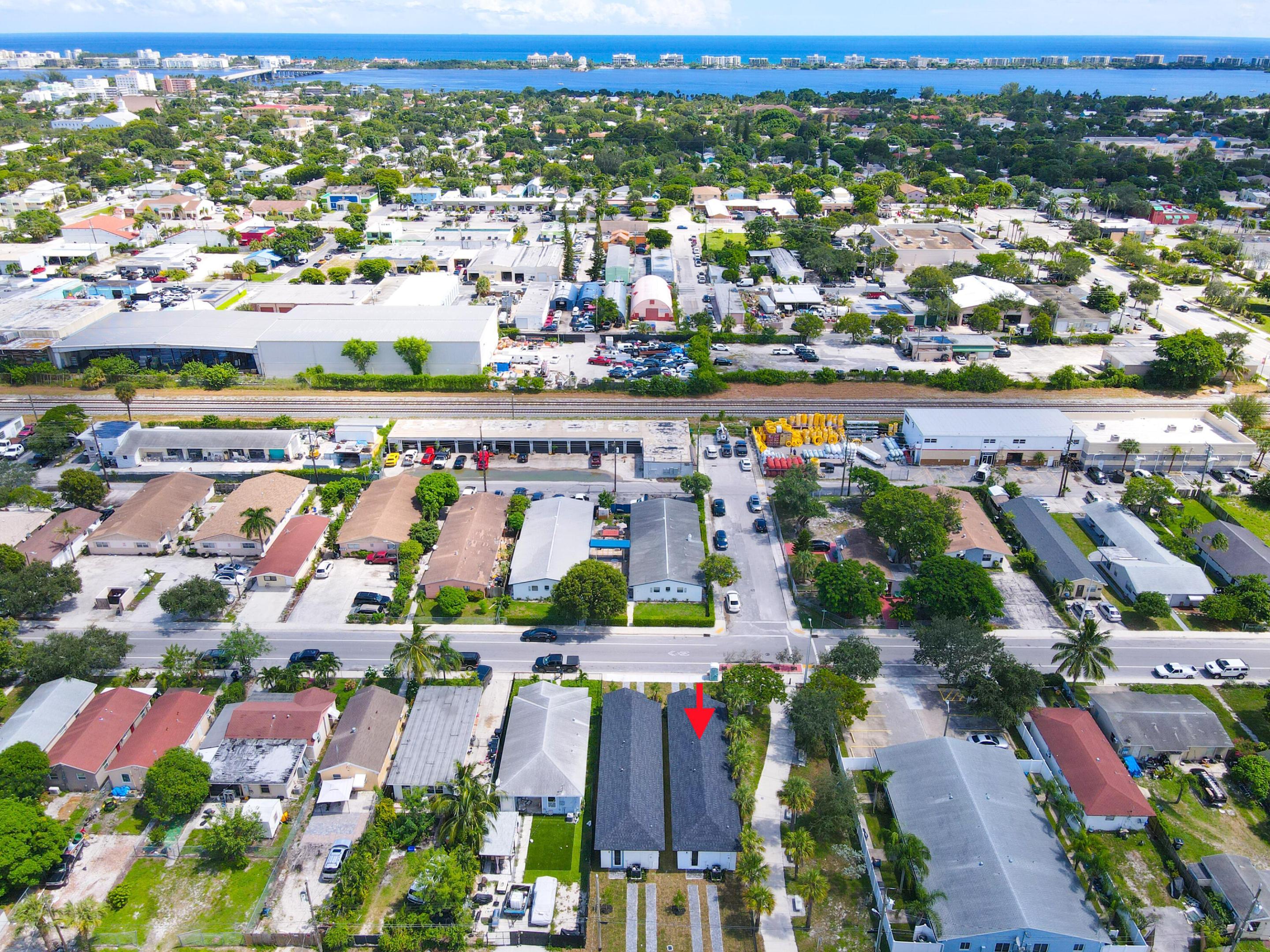 Aerial view of the property marked by a red arrow, with railroad tracks and waterways beyond.