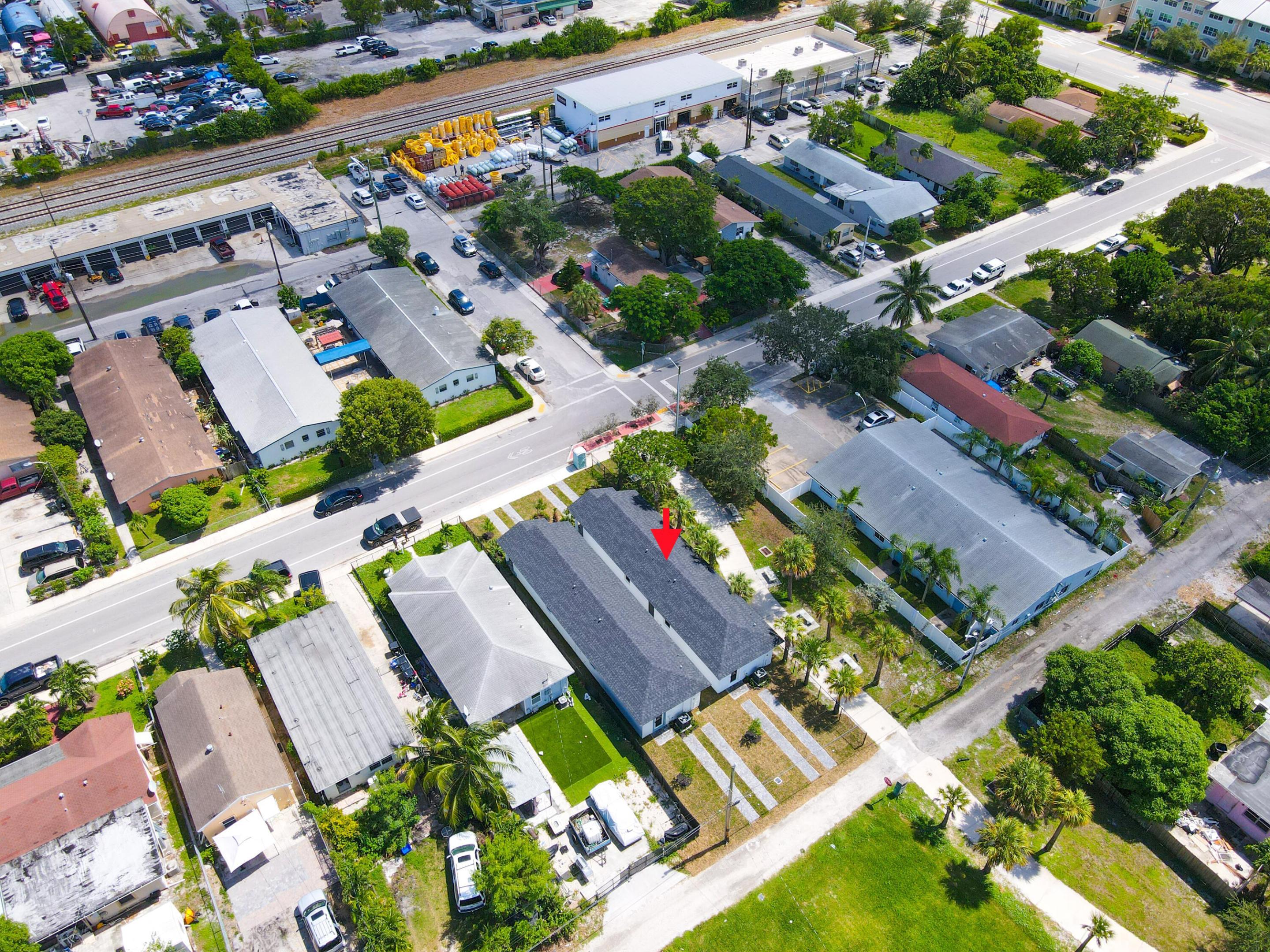 Aerial view of the marked property, a long gray-roofed building among homes and palm trees.
