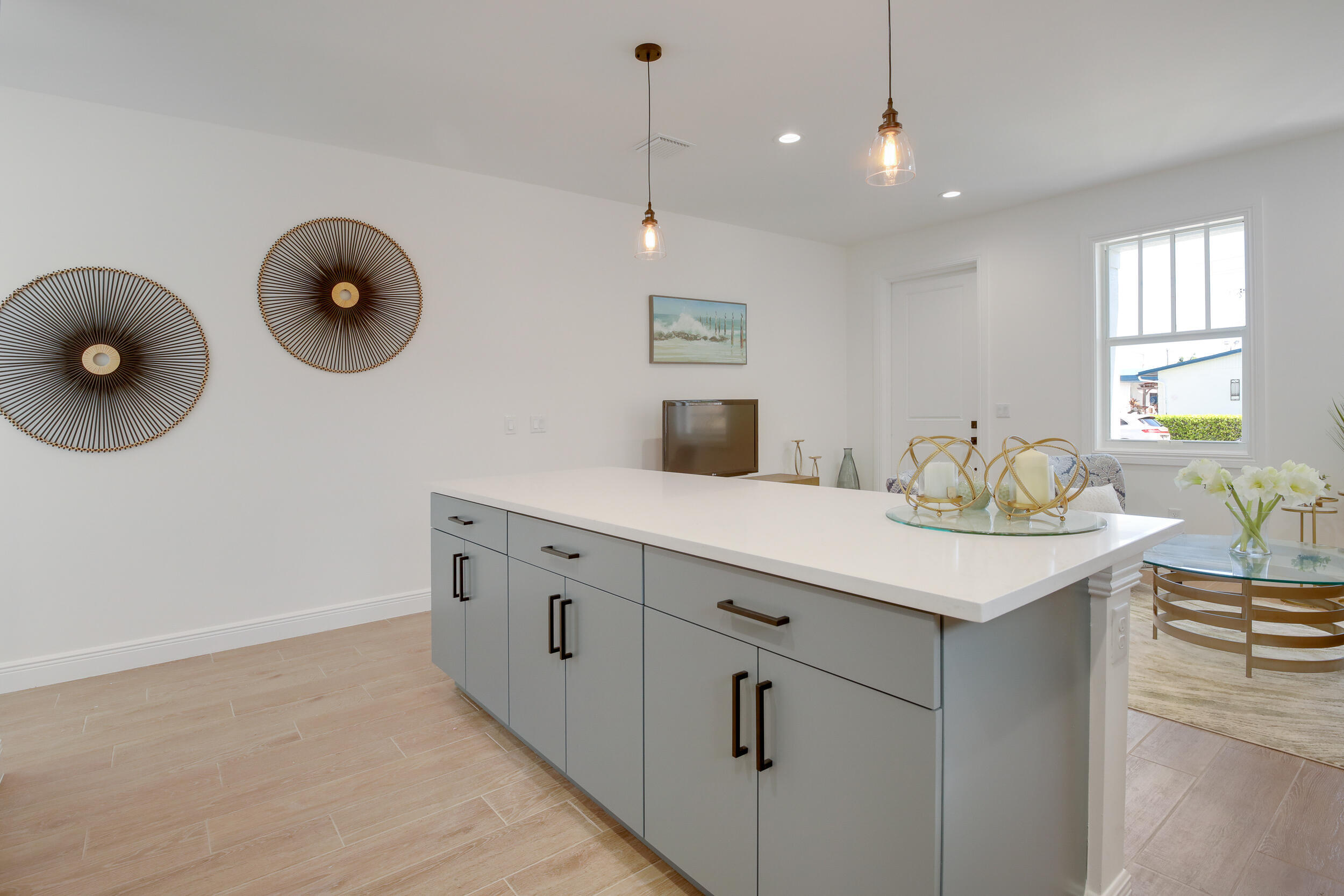 Bright kitchen with a large gray island, white countertop, pendant lights, and adjoining dining area.