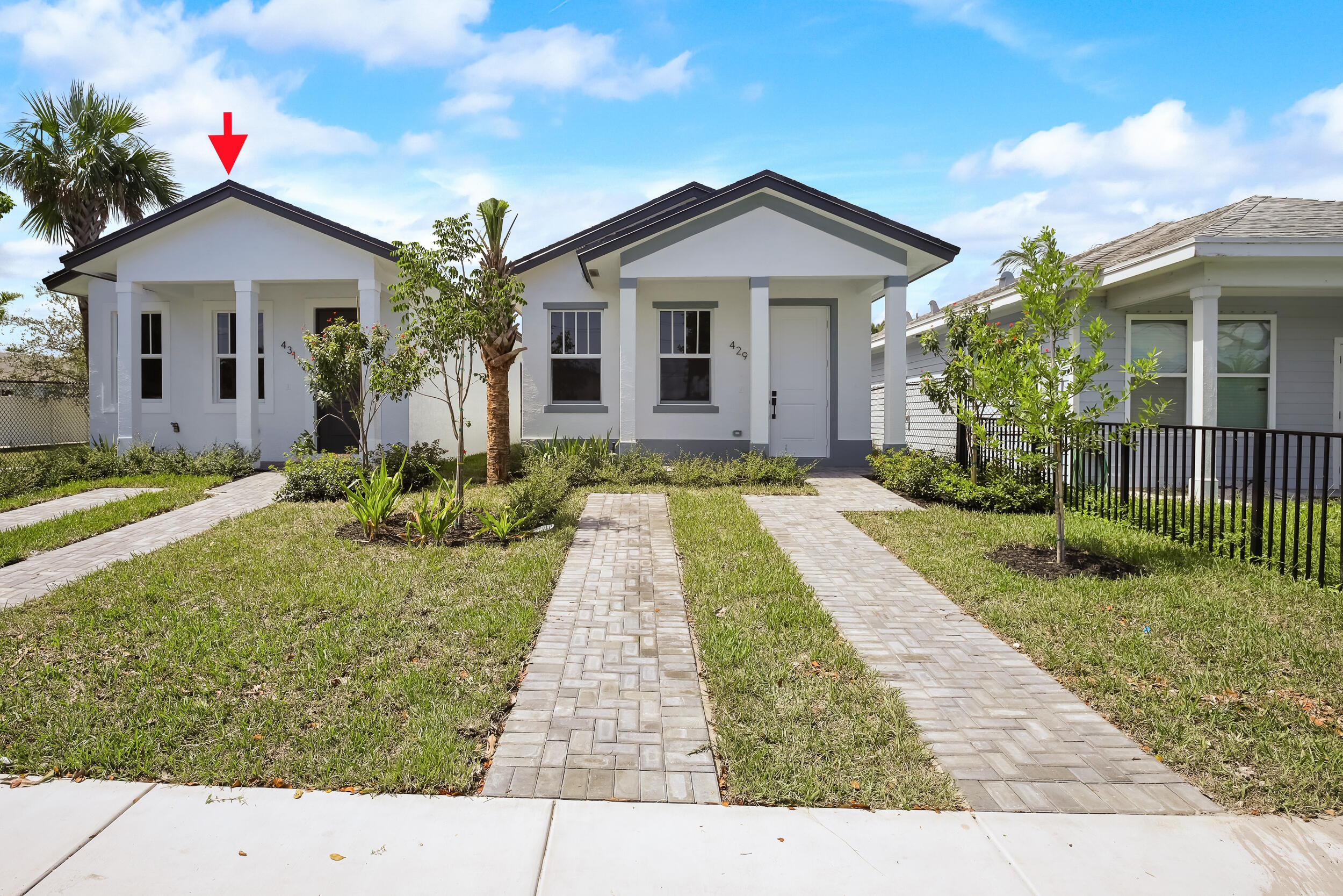 White single-story home with a covered porch, paved walkway, and red arrow pointing to its roof.