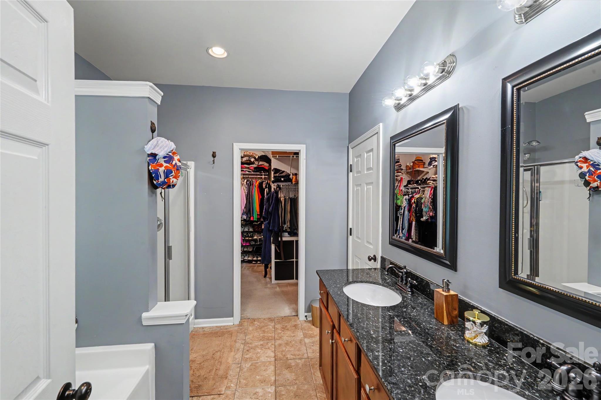 Primary bathroom with a double-sink granite vanity and an open walk-in closet.