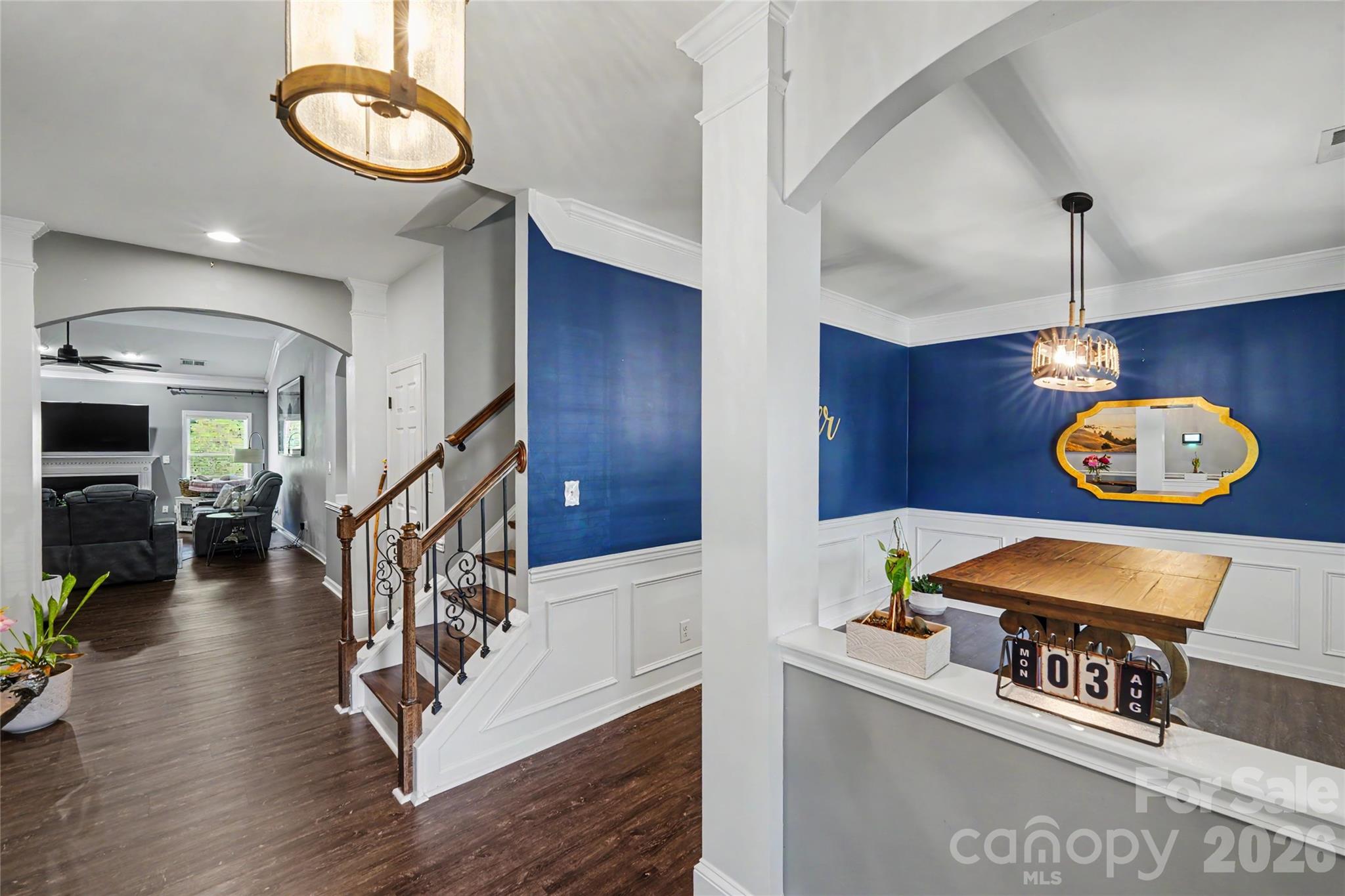 Entry foyer with wood-and-iron staircase beside a blue dining room and adjoining living room.