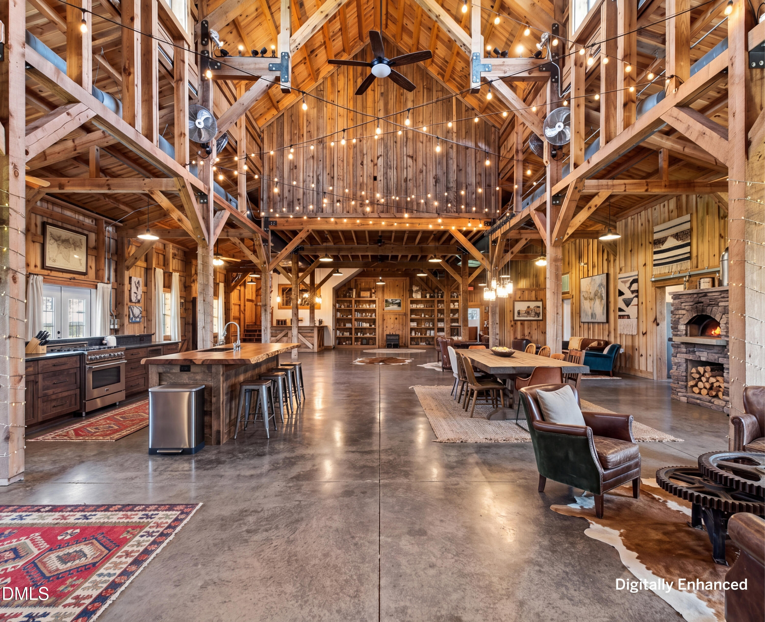Barn-style great room with vaulted timber beams, kitchen island, dining area, and stone fireplace.