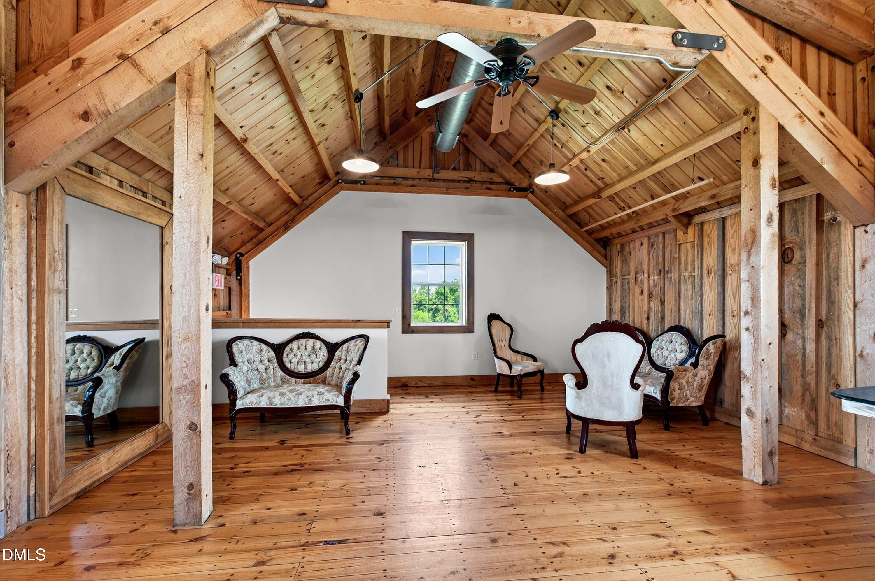 Furnished sitting room with exposed timber beams, vaulted wood ceiling, plank floors, and ornate chairs.