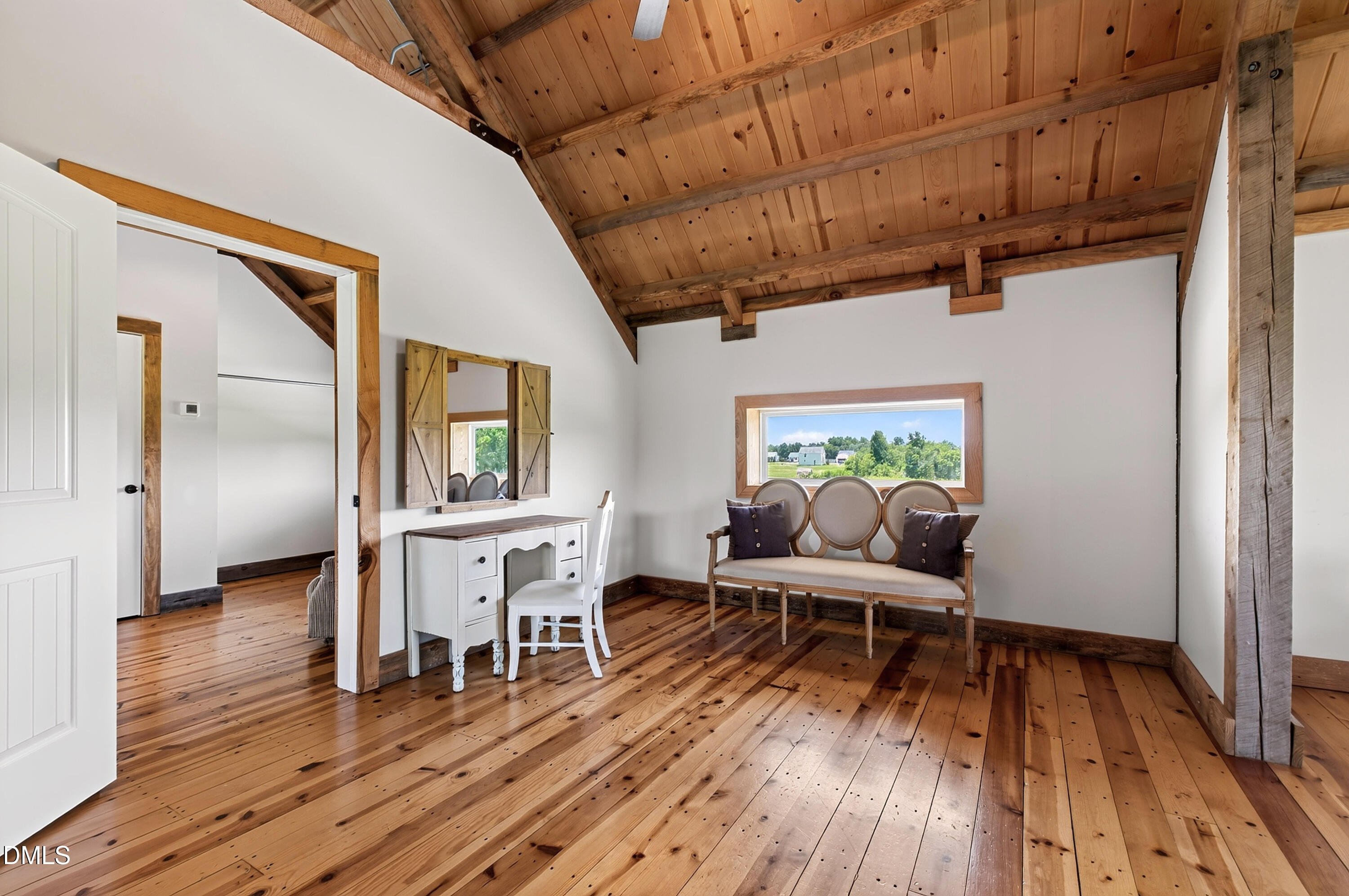 Sitting area with a vaulted wood ceiling, white desk, and upholstered bench beneath a window.