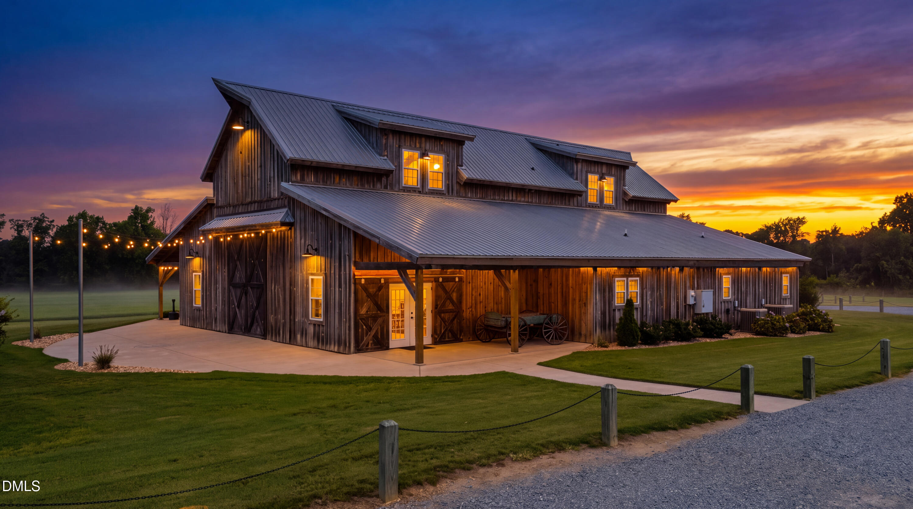 Barn-style home with a metal roof and warmly lit covered porch at sunset.