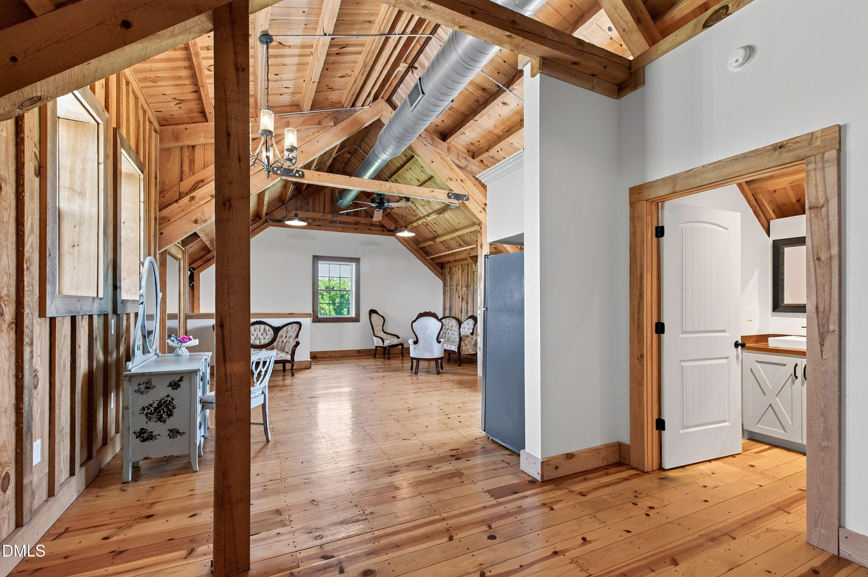 Sitting room with vaulted timber ceiling, exposed beams, and wide-plank wood floors.