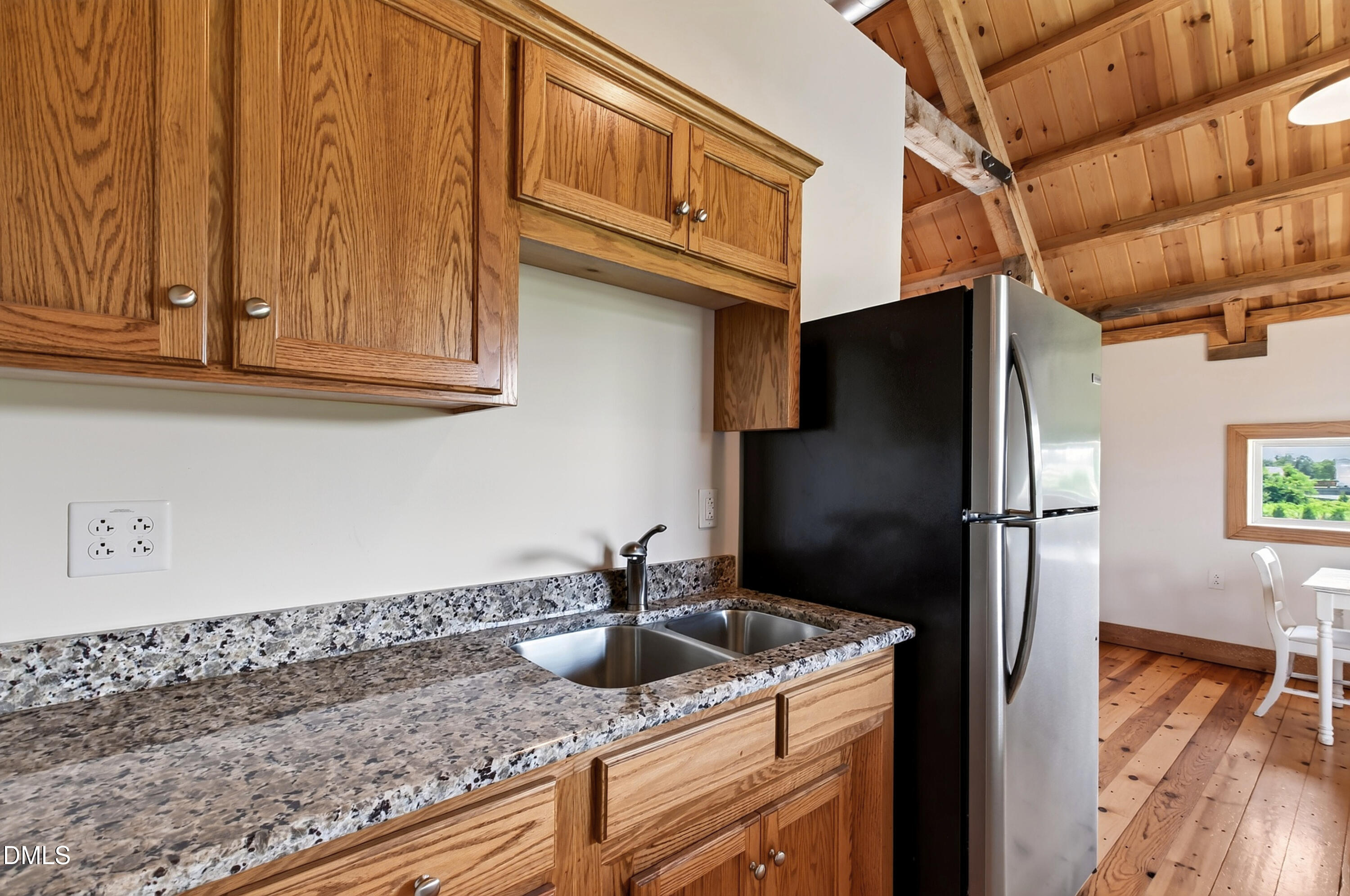 Kitchen with oak cabinets, stone countertops, a double sink, and exposed timber ceiling beams.