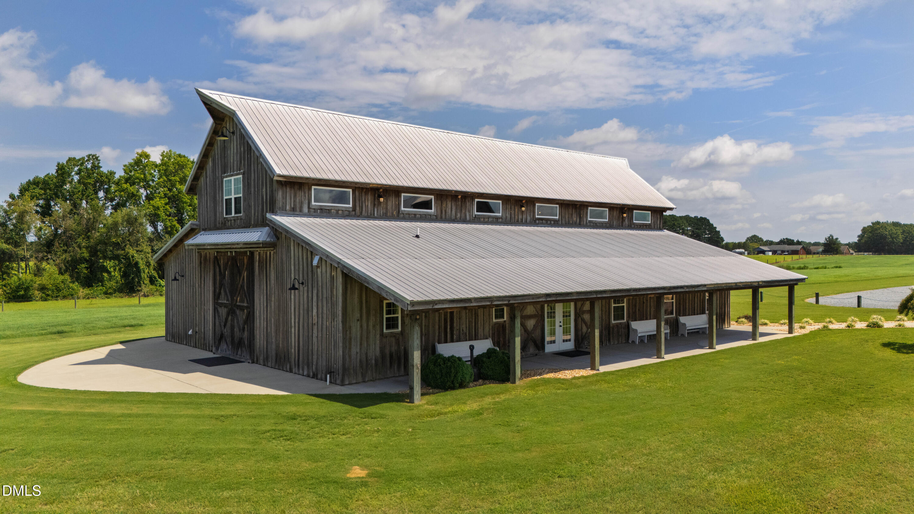 Rustic barn-style building with a long covered porch on a green lawn.