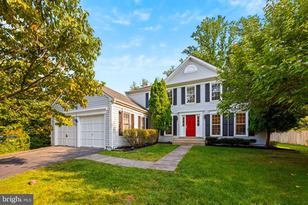 Two-story gray house with black shutters, a red front door, and an attached garage.