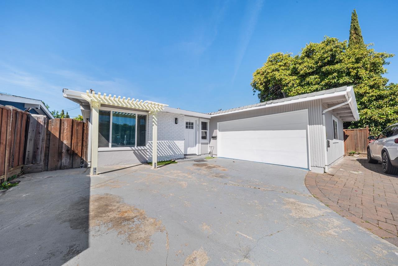Single-story white house with a large garage, front pergola, and broad concrete driveway.