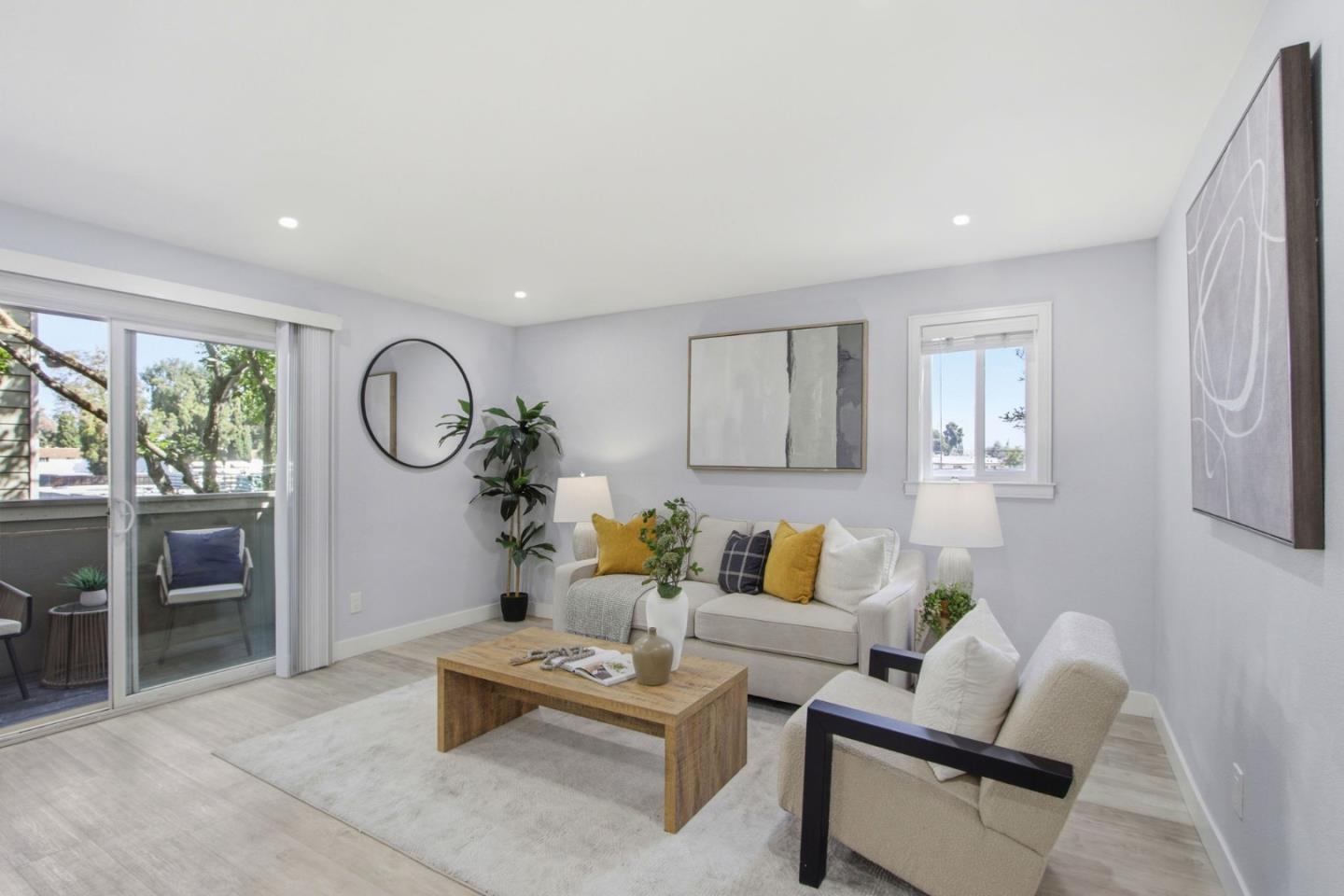 Staged living room with a white sofa, wood coffee table, and sliding doors to a balcony.