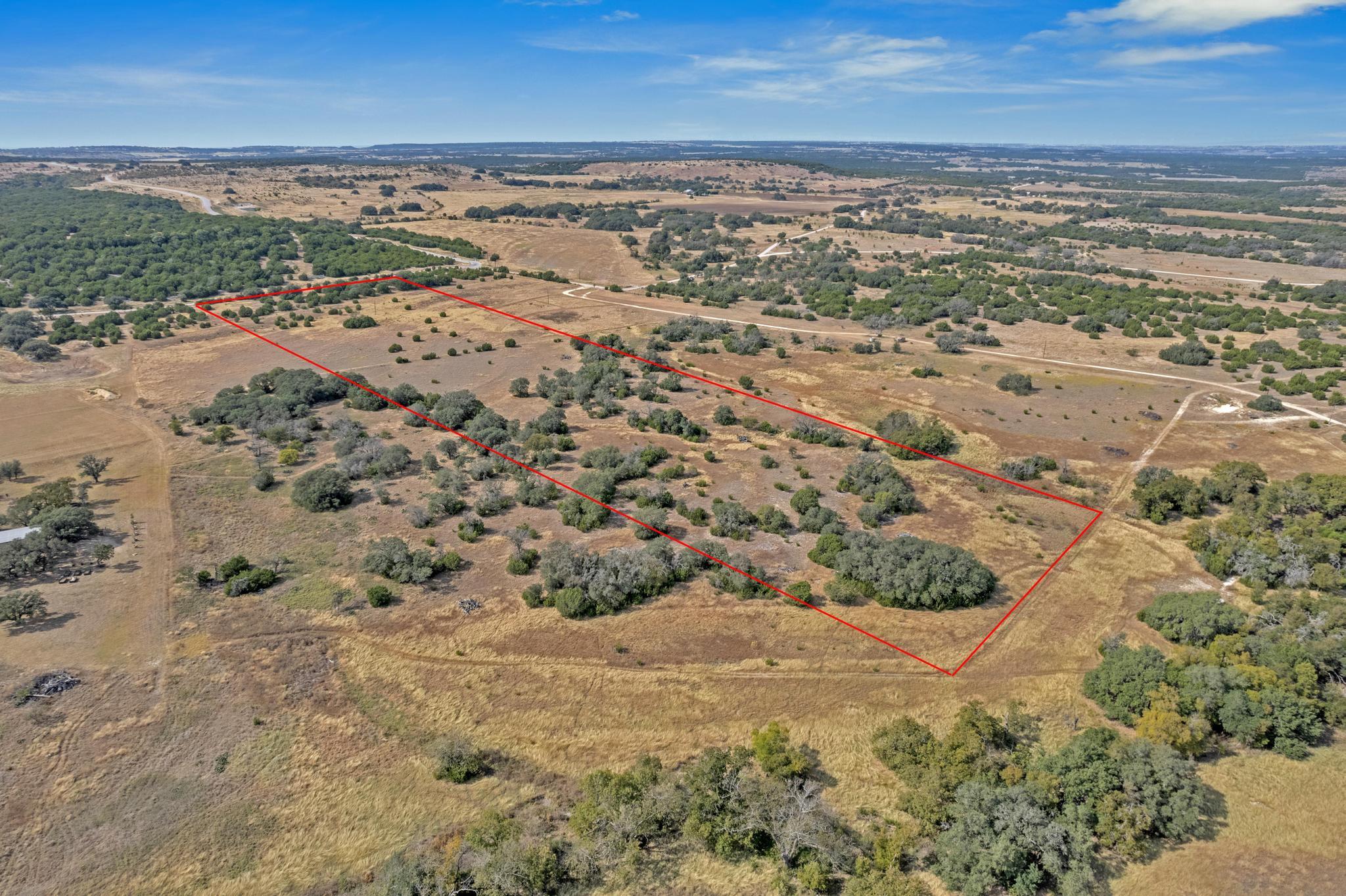 Aerial view of a rural parcel outlined in red, with scattered trees and dry grassland.