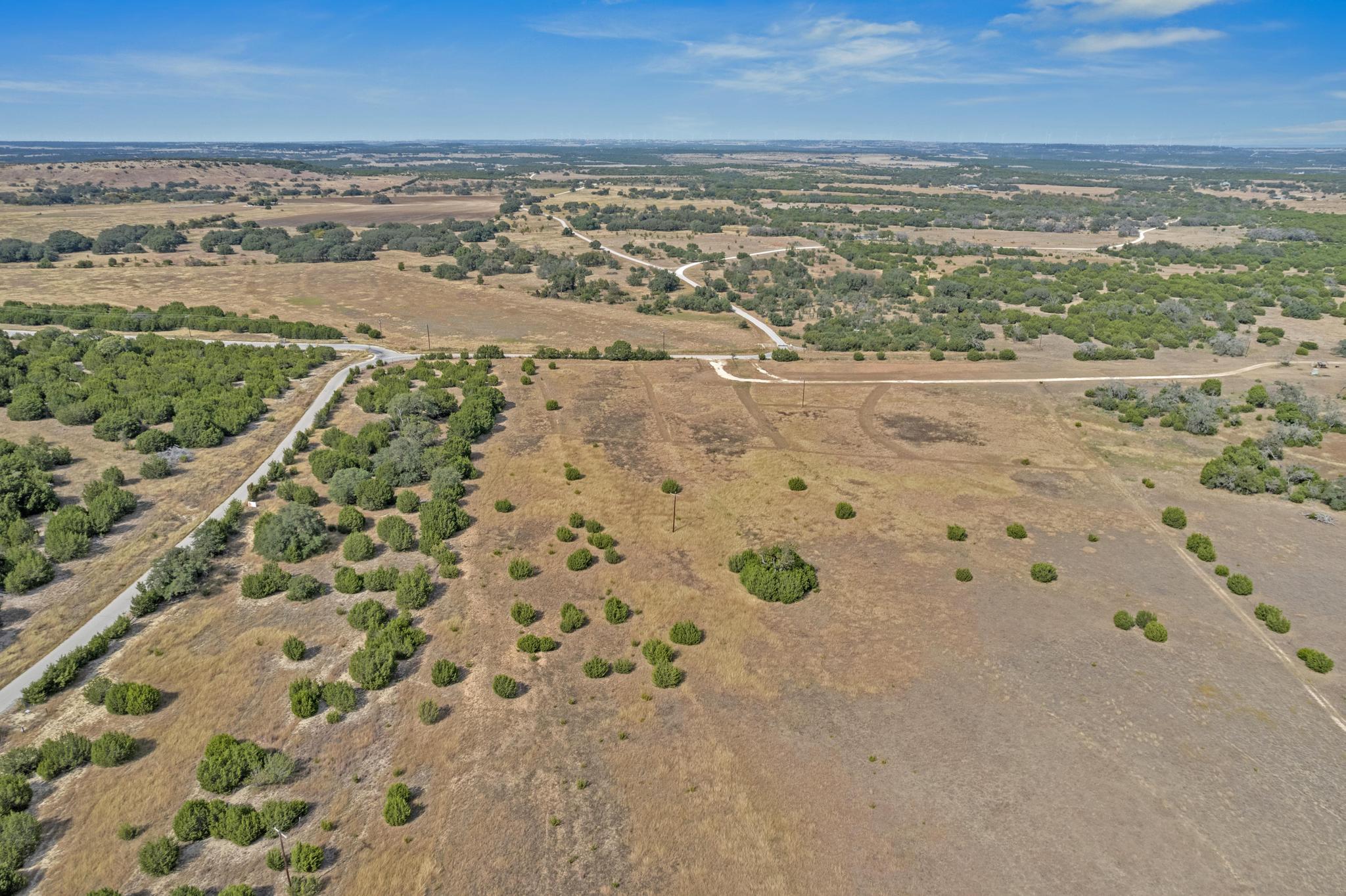 Aerial view of dry, shrub-covered land with ranch roads and a wide rural horizon.
