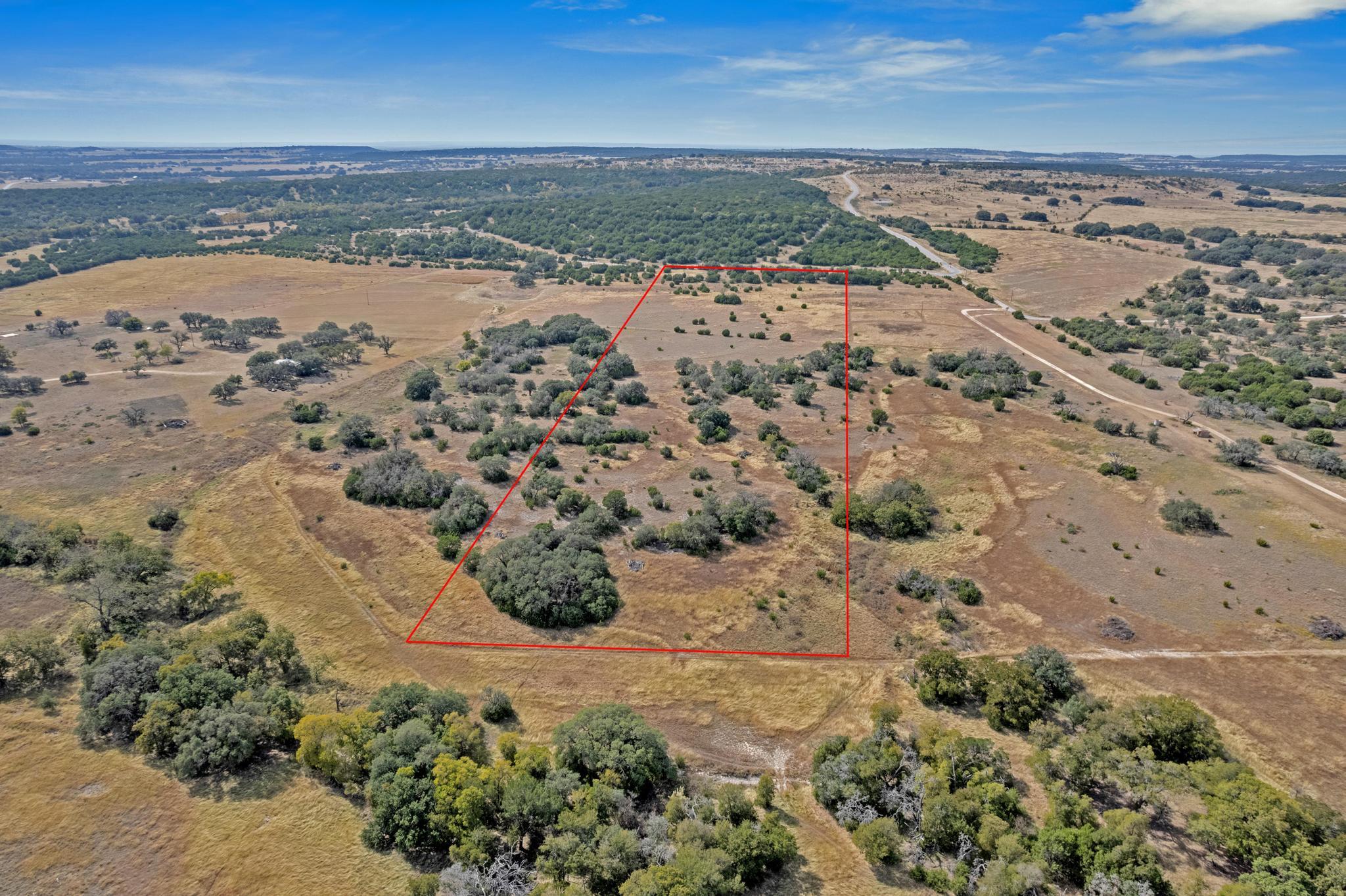 Aerial view of brush-covered rural land outlined in red, with scattered trees and wooded areas nearby.