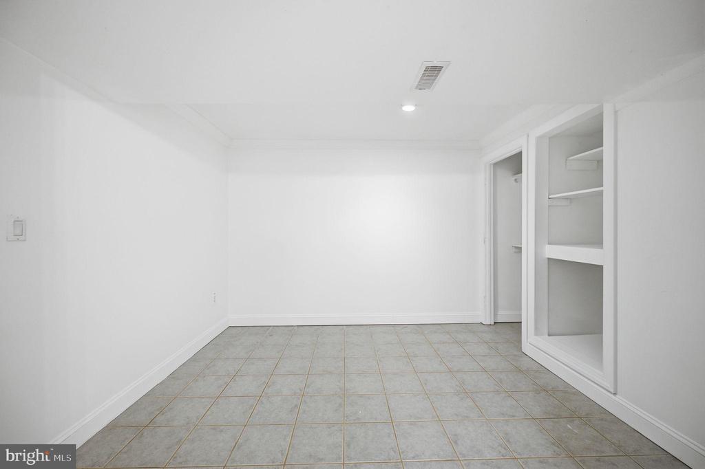 Empty white room with gray tile flooring and built-in open shelving.
