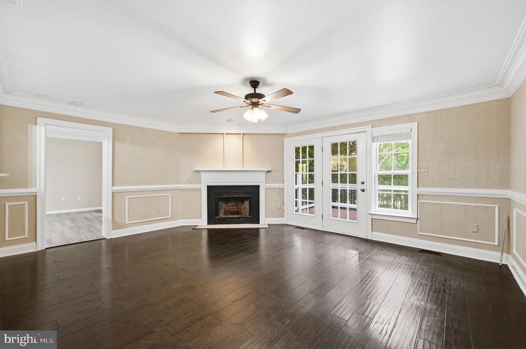 Vacant living room with dark wood floors, a fireplace, and French doors to a deck.