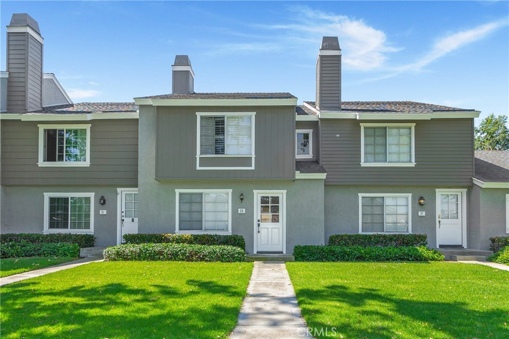 Two-story townhouse with gray siding, white trim, and a walkway through the front lawn.