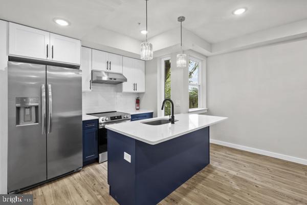 Kitchen with a navy-blue island, white cabinetry, and stainless steel appliances.