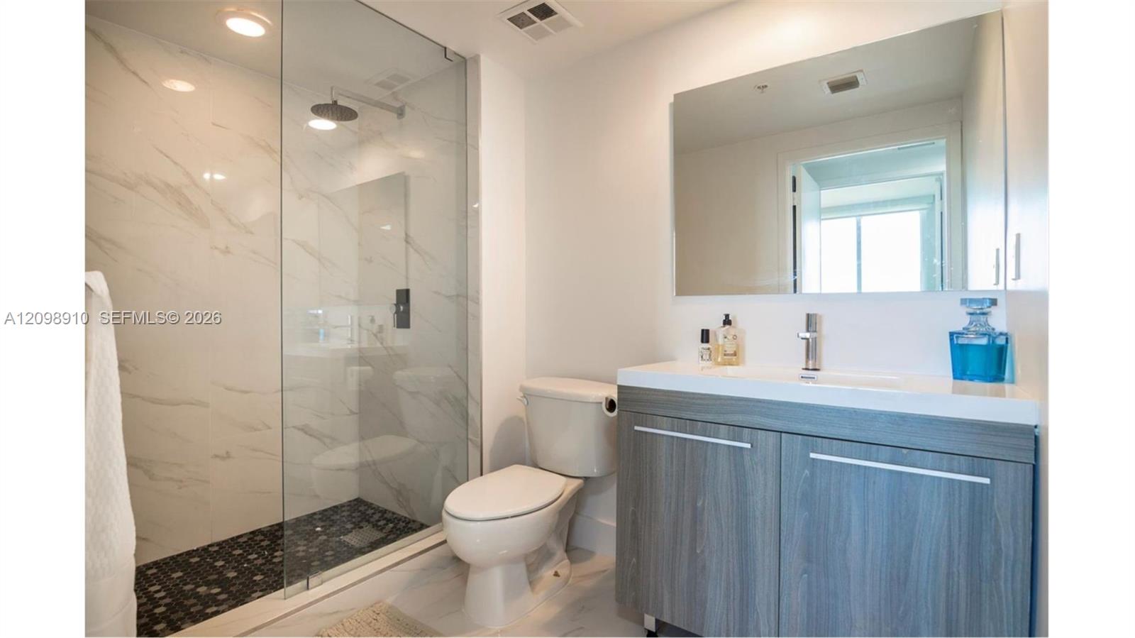 Modern bathroom with a marble-look glass shower and gray wood vanity.