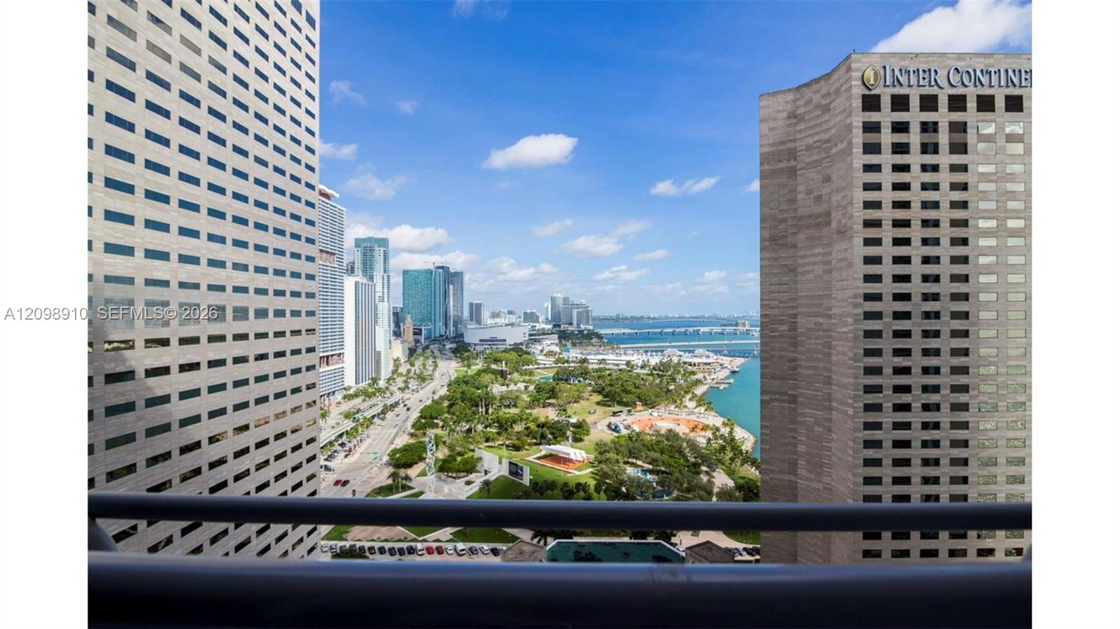 Downtown Miami view from a balcony, with high-rises, a waterfront park, and Biscayne Bay.