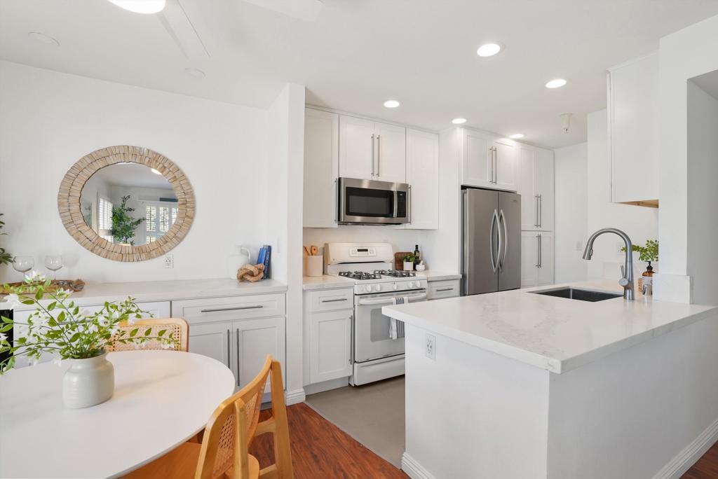 White kitchen with a large island, stainless steel appliances, and a round dining table.