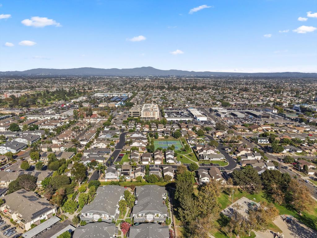 Aerial view of a residential neighborhood with a tennis court and distant hills.