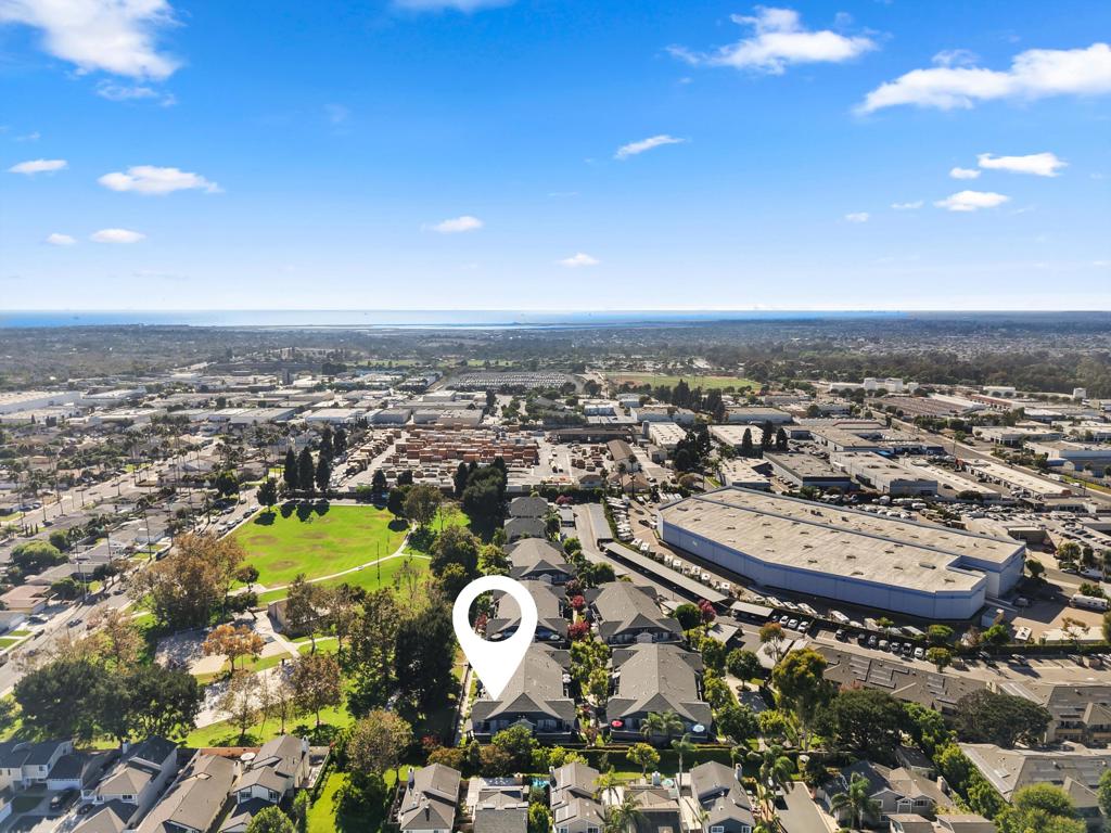 Aerial view of homes and a green park, with the ocean on the horizon.