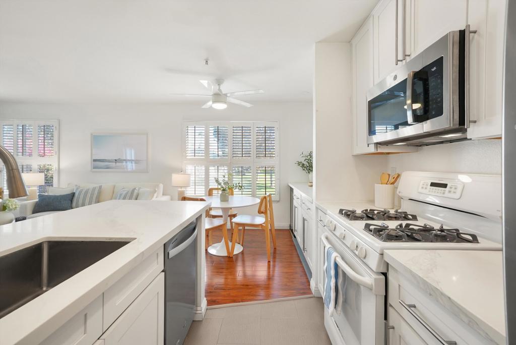 Bright white kitchen with a large sink island, stainless appliances, and an adjoining dining area.