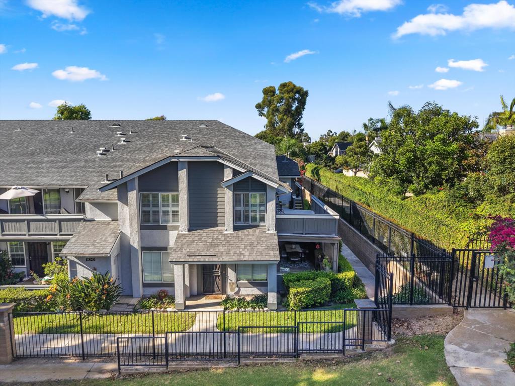 Two-story gray townhouse with a fenced landscaped yard and gated walkway, seen from above.