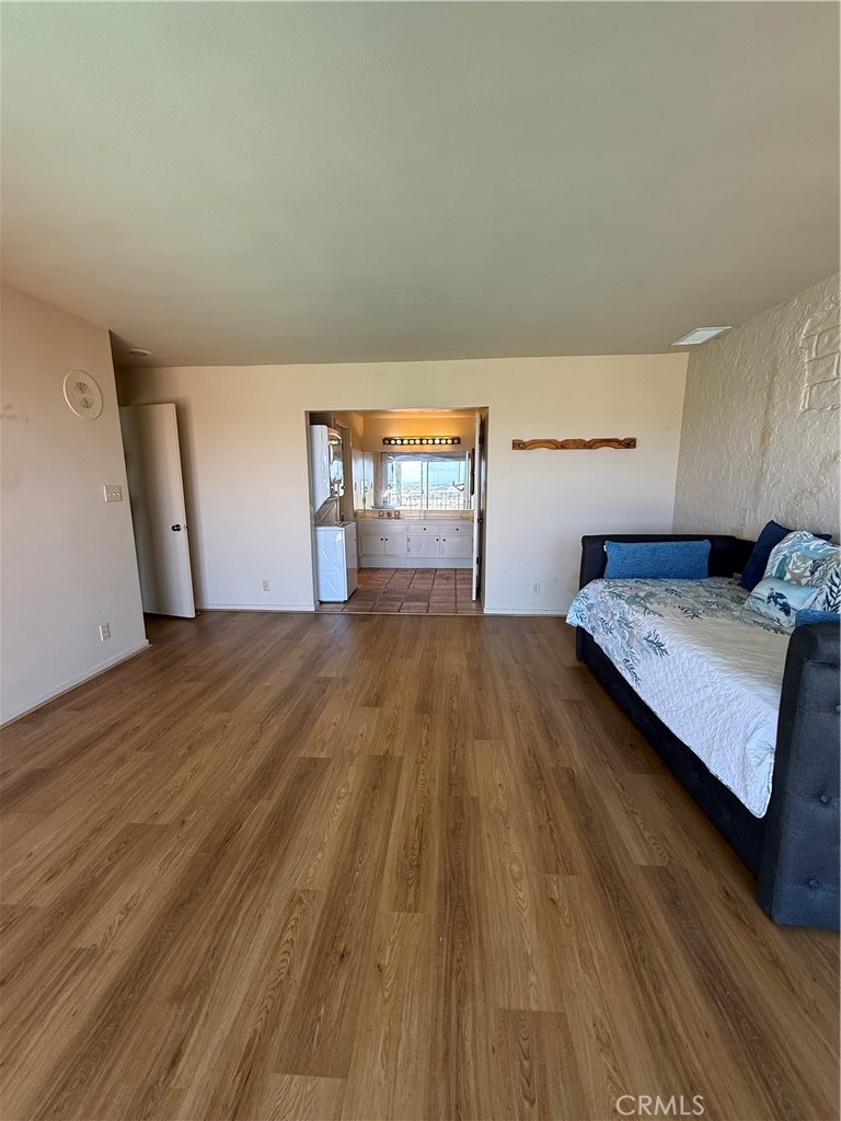 Living room with wood-look flooring and a dark sofa; a tiled kitchen and water view are visible beyond.