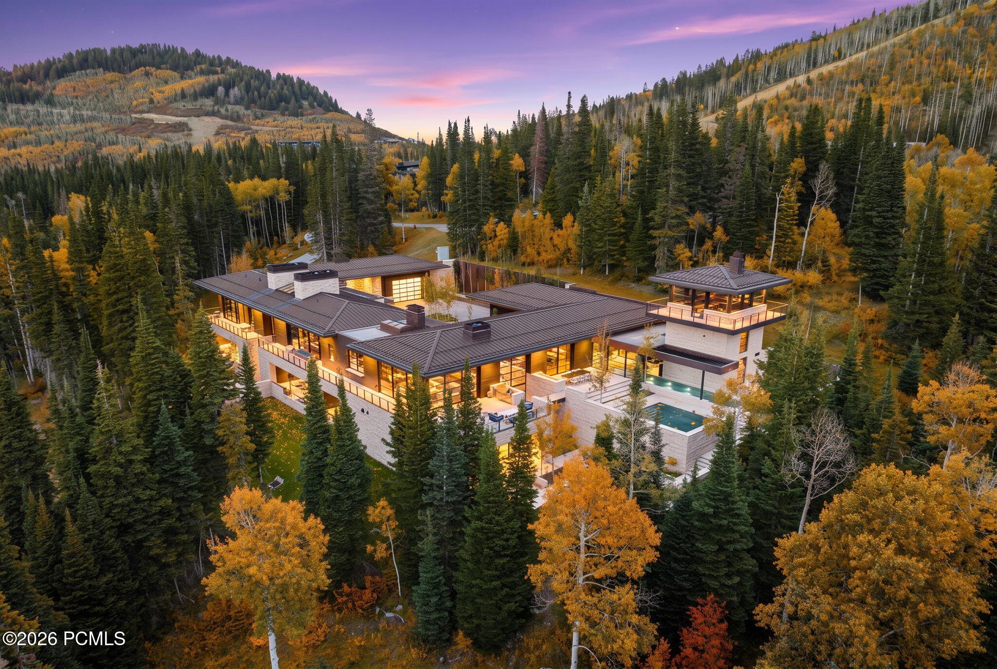 Modern home and outdoor pool nestled among evergreen trees and golden autumn aspens.