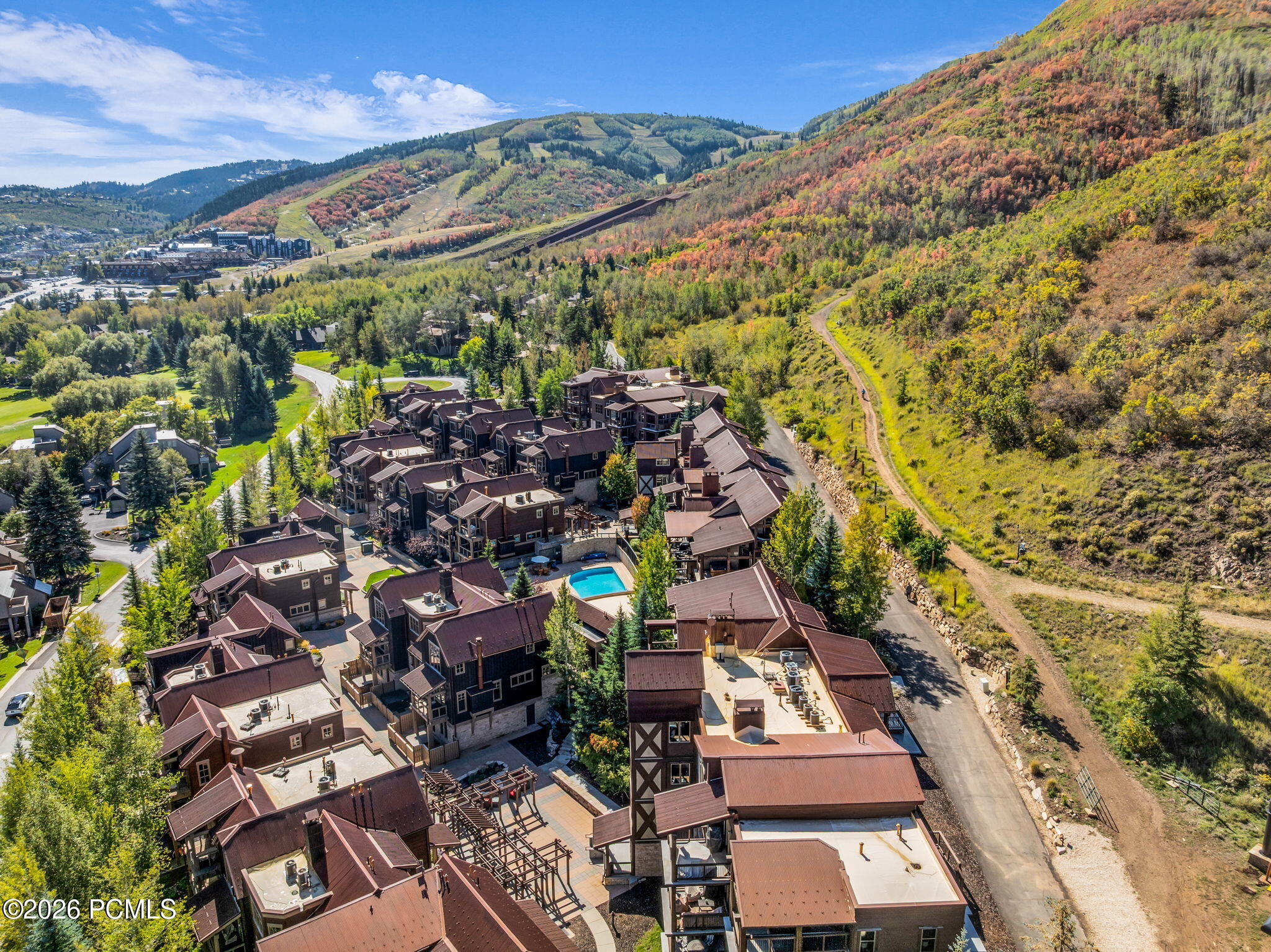 Park City condominiums with a courtyard pool below an autumn-colored mountainside.