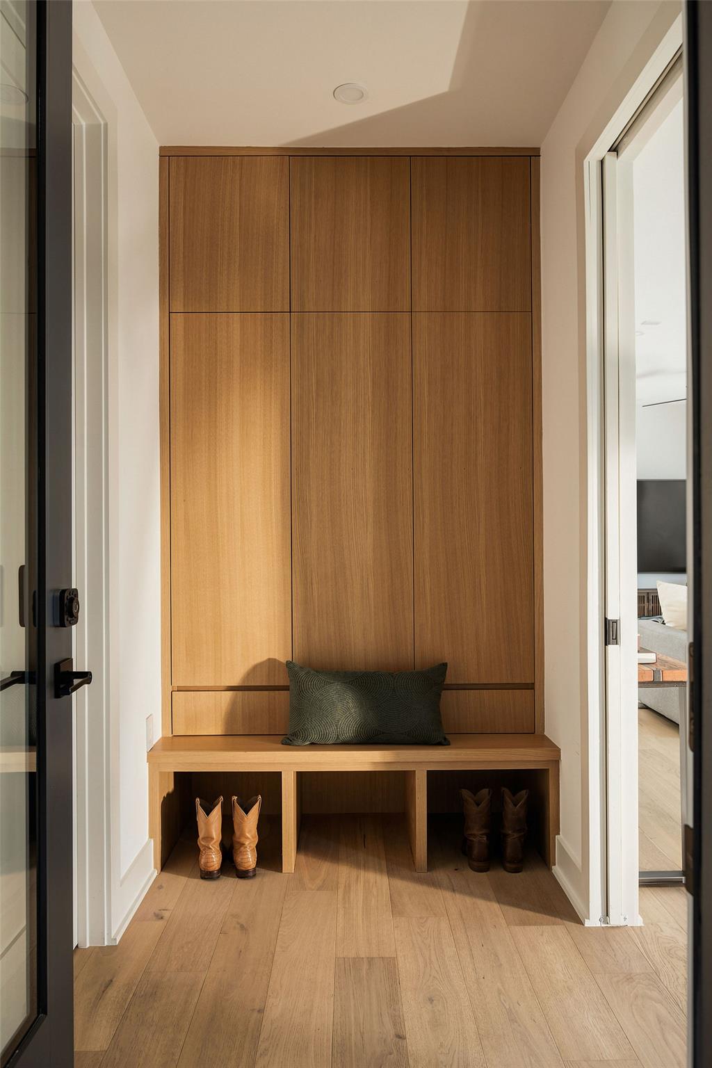 Entryway with a tall wood-paneled built-in and bench, boots in the cubbies below.