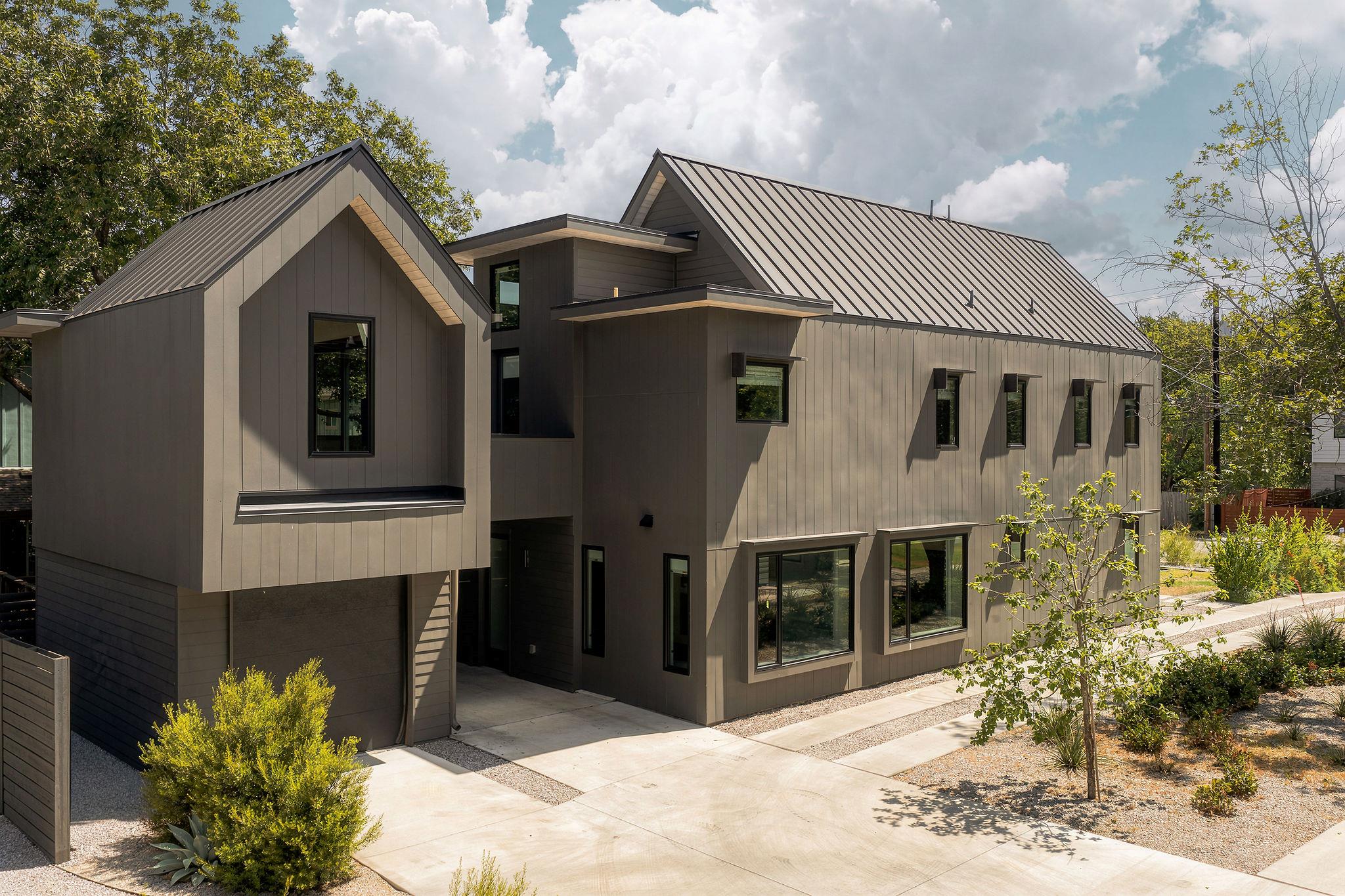 Modern two-story home with angular metal roofs, dark siding, and drought-tolerant landscaping.