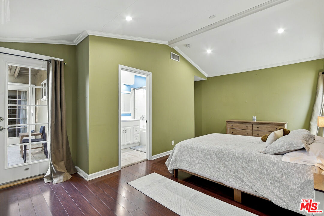 Bedroom with olive-green walls, dark wood floors, and an adjoining bathroom.