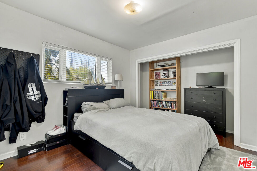 Bedroom with a large bed, hardwood floors, and a recessed bookcase and dresser.