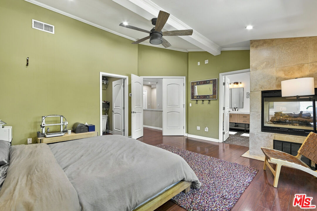 Bedroom with olive-green walls, a large bed, and a stone fireplace.