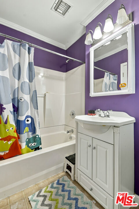 Bathroom with purple walls, a white vanity, and a colorful cartoon-patterned shower curtain.