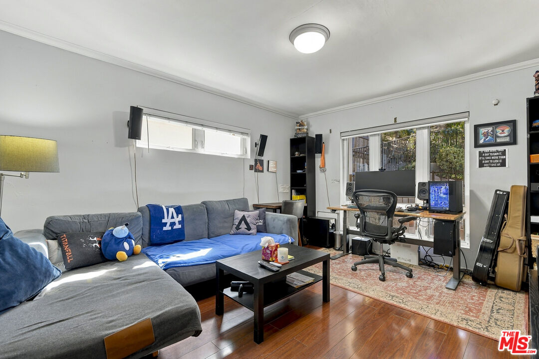 Living room with a gray sectional, blue throw, and computer desk by large windows.