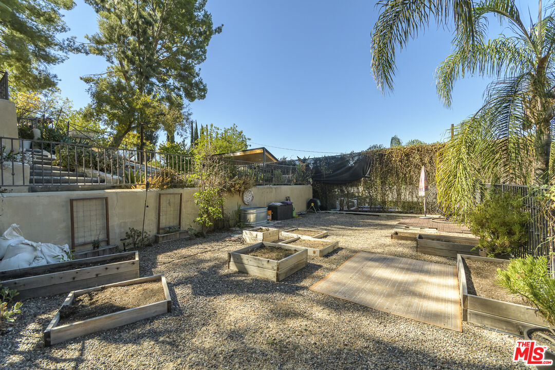 Backyard with raised wooden garden beds, gravel landscaping, and a large rectangular wooden platform.