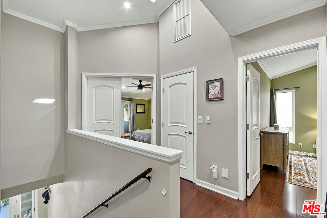 Upstairs hallway with dark wood floors, a half wall, and doorways to furnished rooms.