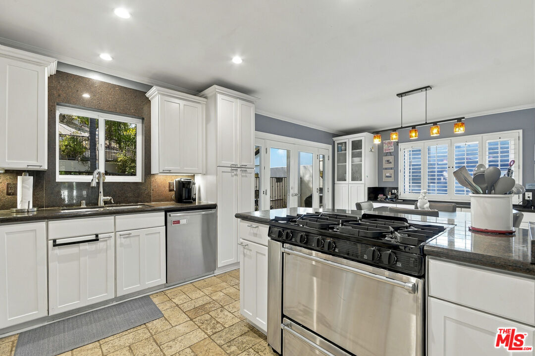 Kitchen with white cabinetry, dark stone counters, and a large stainless-steel range.